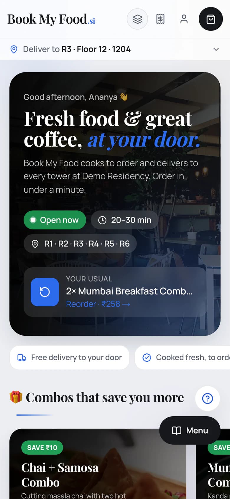 The Book My Food ordering site on a phone in the Neo Light theme: Deliver to R3 · Floor 12 · 1204, a café-photo hero saying Good afternoon, Ananya and Fresh food & great coffee, at your door, with Open now, 20–30 min and towers R1–R6, a Your usual card to reorder 2× Mumbai Breakfast Combo for ₹258, and Combos that save you more starting with the Chai + Samosa Combo at ₹70 (save ₹10).